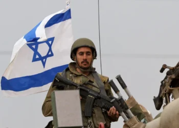 Foto soldado de Israel com arma e bandeira de Israel ao fundo