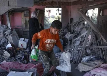 Criança palestina resgata pertences dos escombros de uma casa atingida por um bombardeio israelense noturno em Rafah, no sul da Faixa de Gaza - (Foto: Divulgação/ AFP/CP)