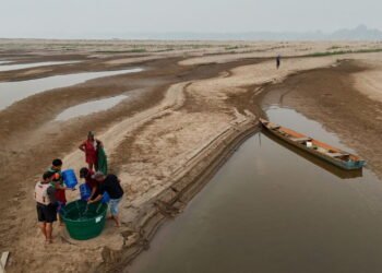 Homens coletam água potável próximo a um banco de areia do Rio Madeira na Comunidade de Paraizinho, em Humaitá (Michael Dantas/AFP)