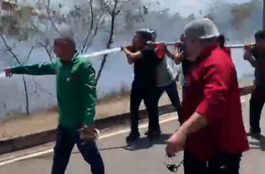 Trabalhadores combatem chamas com mangueira (Foto: Reprodução/Redes Sociais)
